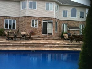 Brick house with large windows, outdoor seating, and a blue swimming pool.