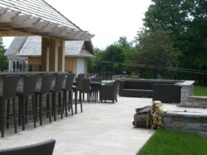 Outdoor patio with a bar-style seating area, lounge furniture, and a stone fire pit.