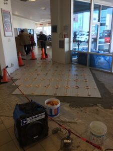 Renovation scene in a lobby with new tiles, construction tools, and workers nearby.