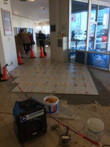 Renovation in a building lobby with new tile being laid, construction materials visible.