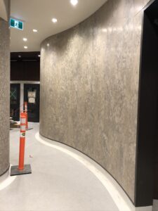 Curved hallway showing textured beige wall, safety cone, and exit sign above.